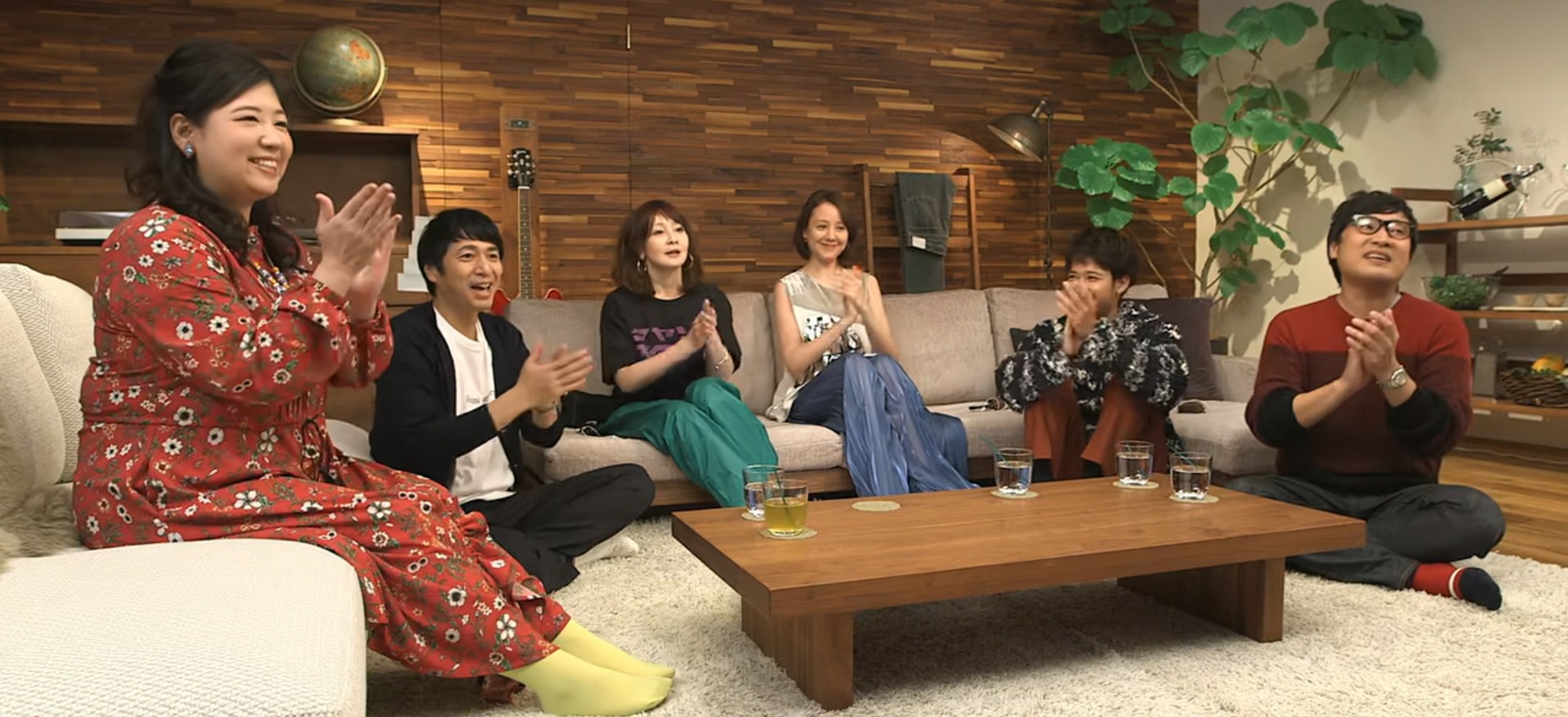 Six Terrace House cast members seated together in the show’s living room.